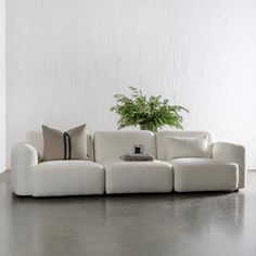 a white couch sitting next to a potted plant