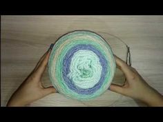 two hands holding a green and blue crochet hat