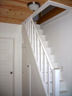 an empty room with white stairs and wood paneling