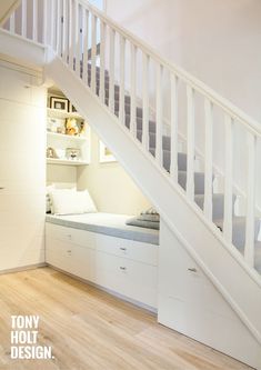 there is a bed under the stairs in this room with white walls and flooring