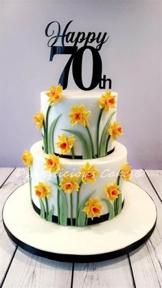 a white cake with yellow flowers and the number seventy on top is sitting on a plate