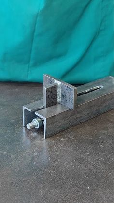 a piece of metal sitting on top of a floor next to a blue sheet covered wall