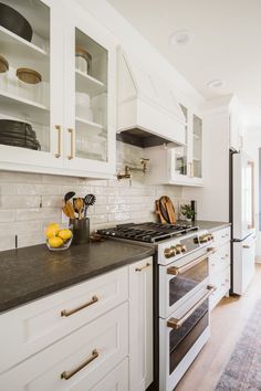 a kitchen with white cabinets and black counter tops, along with an open oven door