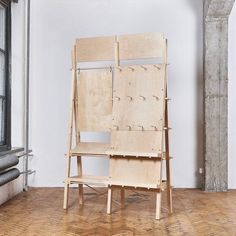 a wooden easel sitting on top of a hard wood floor next to a window