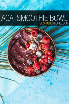 a bowl filled with blueberries and raspberries on top of a palm leaf