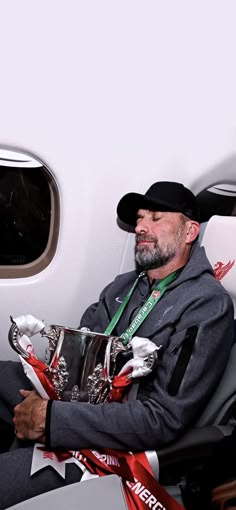 a man sitting on an airplane seat holding a trophy