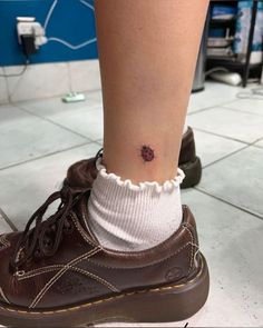 a woman's foot with a tiny flower tattoo on her left ankle and the bottom part of her shoe