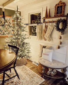 a christmas tree is lit up in the corner of a room with white walls and wood floors