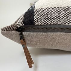 a close up of a pillow on a white surface with a brown zippered closure