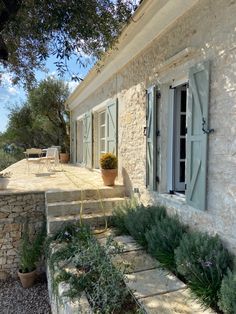 a stone house with green shutters and plants