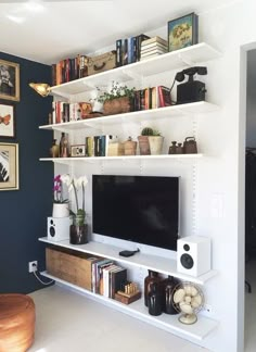 a living room filled with furniture and a flat screen tv on top of a white shelf