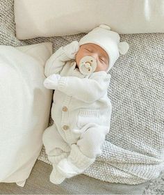 a baby laying on top of a bed next to pillows