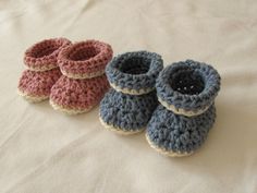 three crocheted baby booties sitting on top of a bed