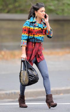 a woman is walking down the street talking on her cell phone and holding a purse