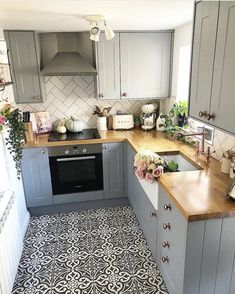 the kitchen is decorated in grey and white with wood countertops, tile flooring, and wooden counters