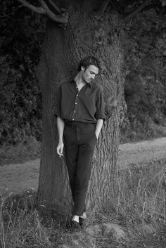 a man standing next to a tree in the grass