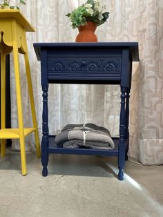 a blue table with two yellow stools next to it and a potted plant