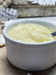 a white bowl filled with food on top of a wooden table next to crackers