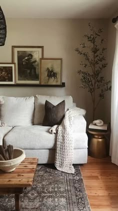 a living room with white couches and pictures on the wall above them, along with a coffee table