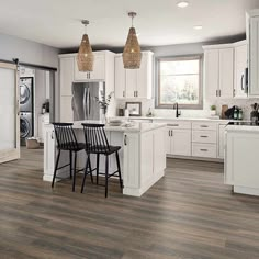 a kitchen with white cabinets and wood floors