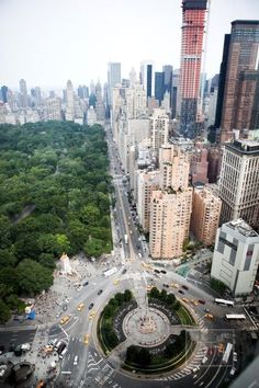 an aerial view of a city with tall buildings and lots of trees in the foreground