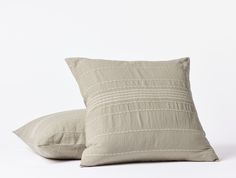 two pillows sitting next to each other on a white surface