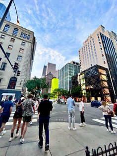 people are standing on the sidewalk in front of tall buildings