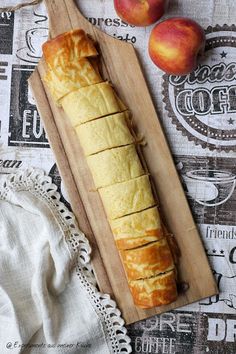 a loaf of bread sitting on top of a cutting board next to two peaches