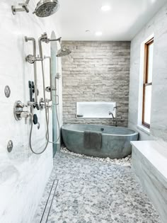 a bathtub and shower in a bathroom with stone walls, flooring and tile