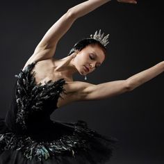 a woman in a black dress and tiara is posing with her arms stretched out