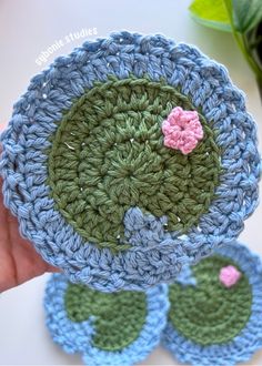 crocheted blue and green pot holders with pink flower