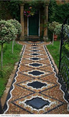 an outdoor walkway made out of cobblestones and stones with a green door in the background