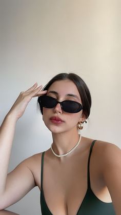 a woman in a green dress wearing black eyeglasses and pearls on her head