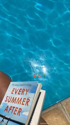 a book sitting on the edge of a swimming pool next to a person's legs