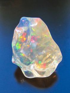 an opalite stone sitting on top of a blue surface with white and green colors