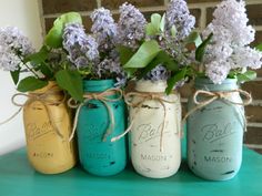 four mason jars with flowers in them on a table