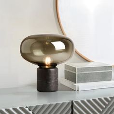 a table lamp sitting on top of a white shelf next to a box and mirror