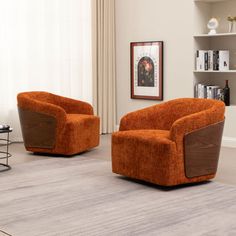 two orange chairs sitting on top of a rug next to a book shelf in a living room