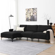 a living room with a black couch and white rug