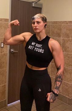 a woman posing for a selfie in a bathroom with her arm up and the words my body, not yours written on it