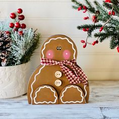 a gingerbread man is sitting next to a potted christmas tree