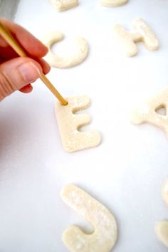 a person holding a toothpick in front of letters on a sheet of food