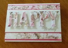 a birthday card with the word happy on it and flowers in pink, white and grey