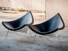 two black and white chairs sitting next to each other on the ground in front of a building