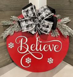 a red and white sign that says believe on it with snowflakes around it