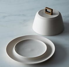 a white plate with a gold ring on it next to an empty saucer and spoon