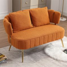 an orange couch sitting on top of a white rug