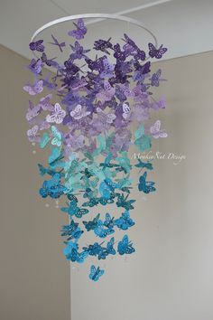 purple and blue butterflies are hanging from a circular chandelier in the corner of a room