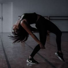 a woman in black shirt and leggings doing a handstand on the floor