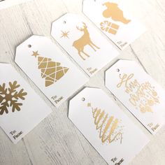 gold and white christmas gift tags on a table with snowflakes, reindeers and trees